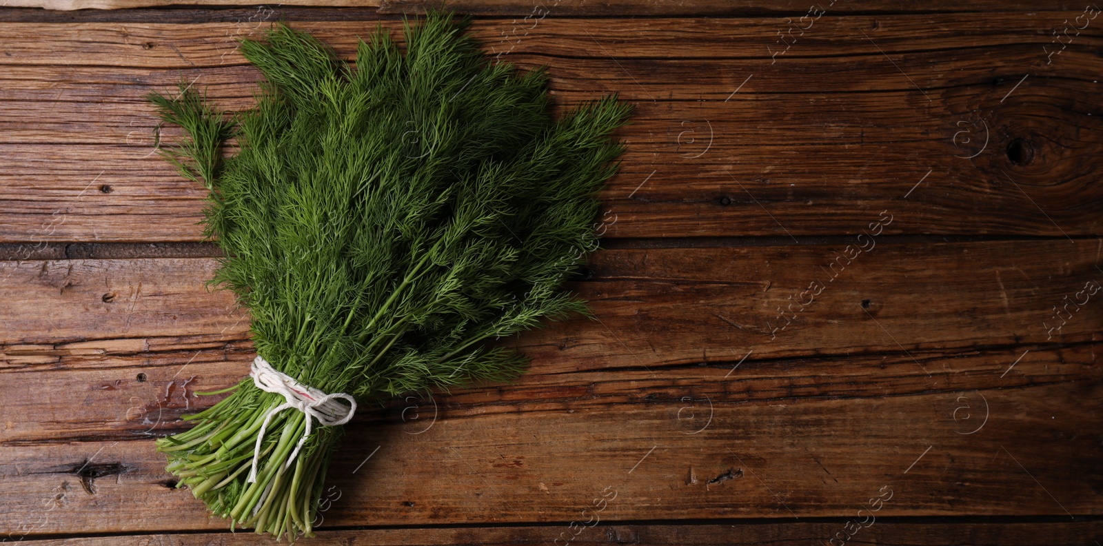 Photo of Bunch of fresh green dill on wooden table, top view. Space for text