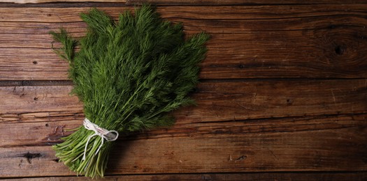 Photo of Bunch of fresh green dill on wooden table, top view. Space for text