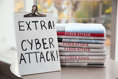 Photo of Clipboard with words EXTRA! CYBER ATTACK! and newspapers on table, closeup