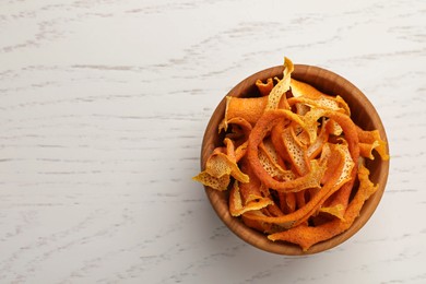 Photo of Dry orange peels in bowl on wooden table, top view. Space for text
