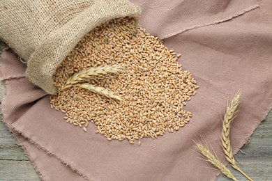 Sack with wheat grains on table, flat lay