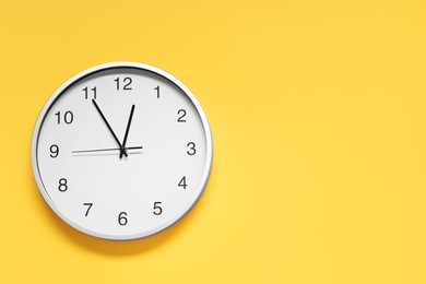 Stylish round clock on yellow background, top view with space for text. Interior element