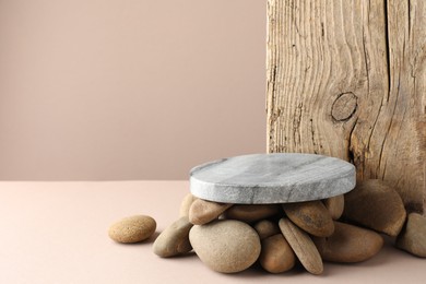 Photo of Presentation for product. Stone podium and pebbles on beige background. Space for text