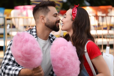 Happy couple with cotton candies at funfair