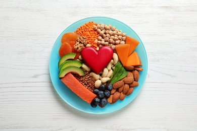 Photo of Plate with heart-healthy products on wooden background, top view