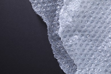 Photo of Transparent bubble wrap on black background, top view. Space for text