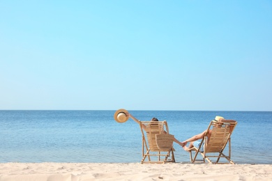 Photo of Young couple relaxing in deck chairs on beach