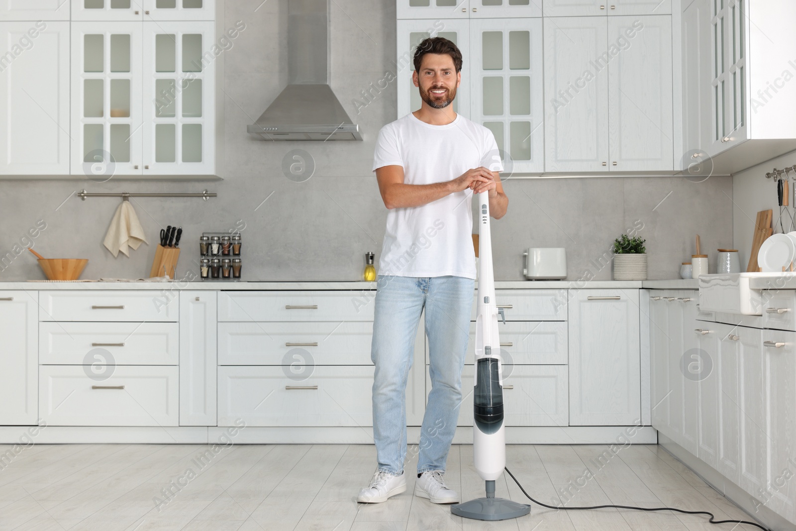 Photo of Happy man with steam mop in kitchen at home