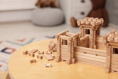 Photo of Wooden fortress and building blocks on table indoors, space for text. Children's toy