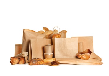 Different fresh bakery products in paper bags on white background