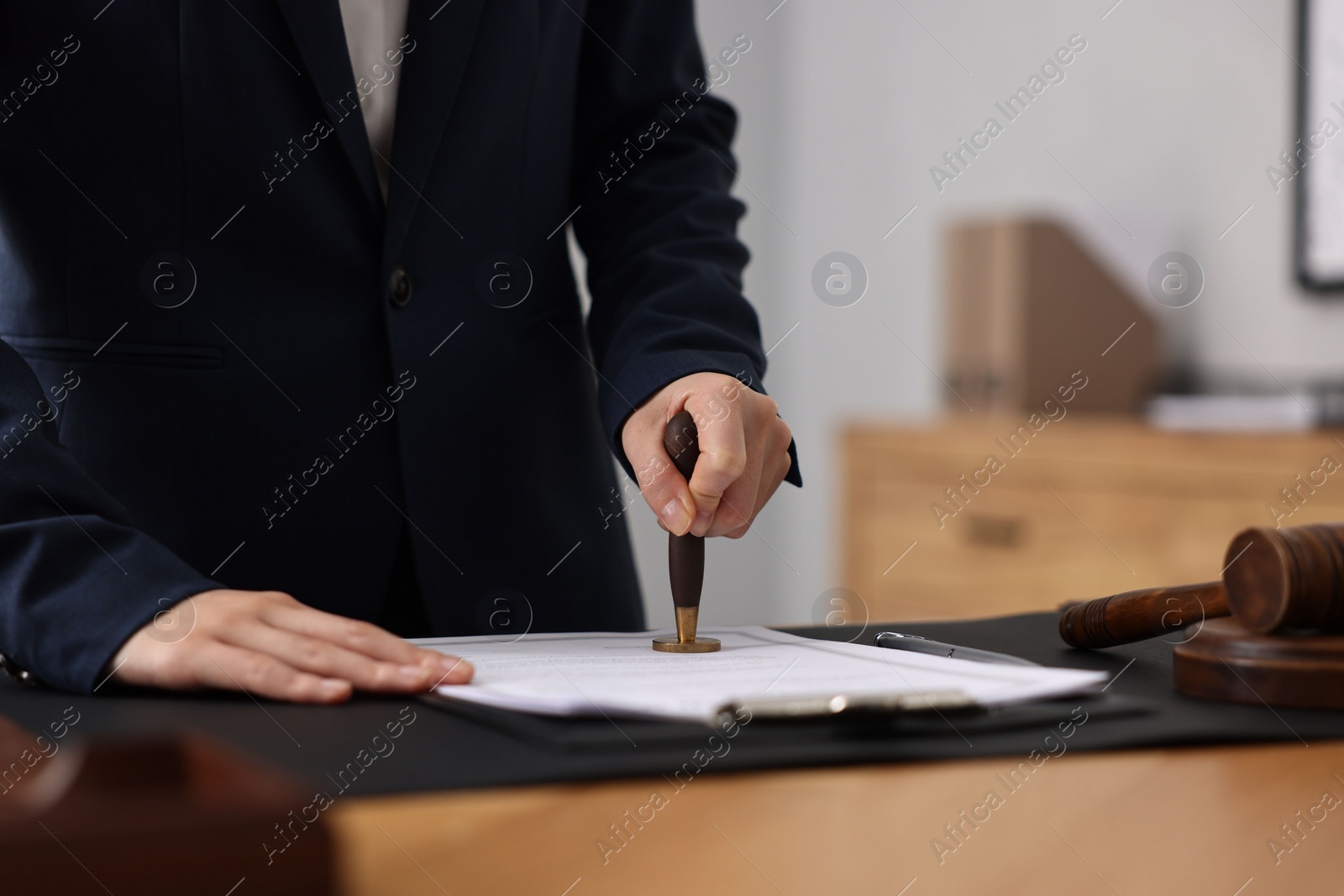Photo of Notary sealing document at table in office, closeup