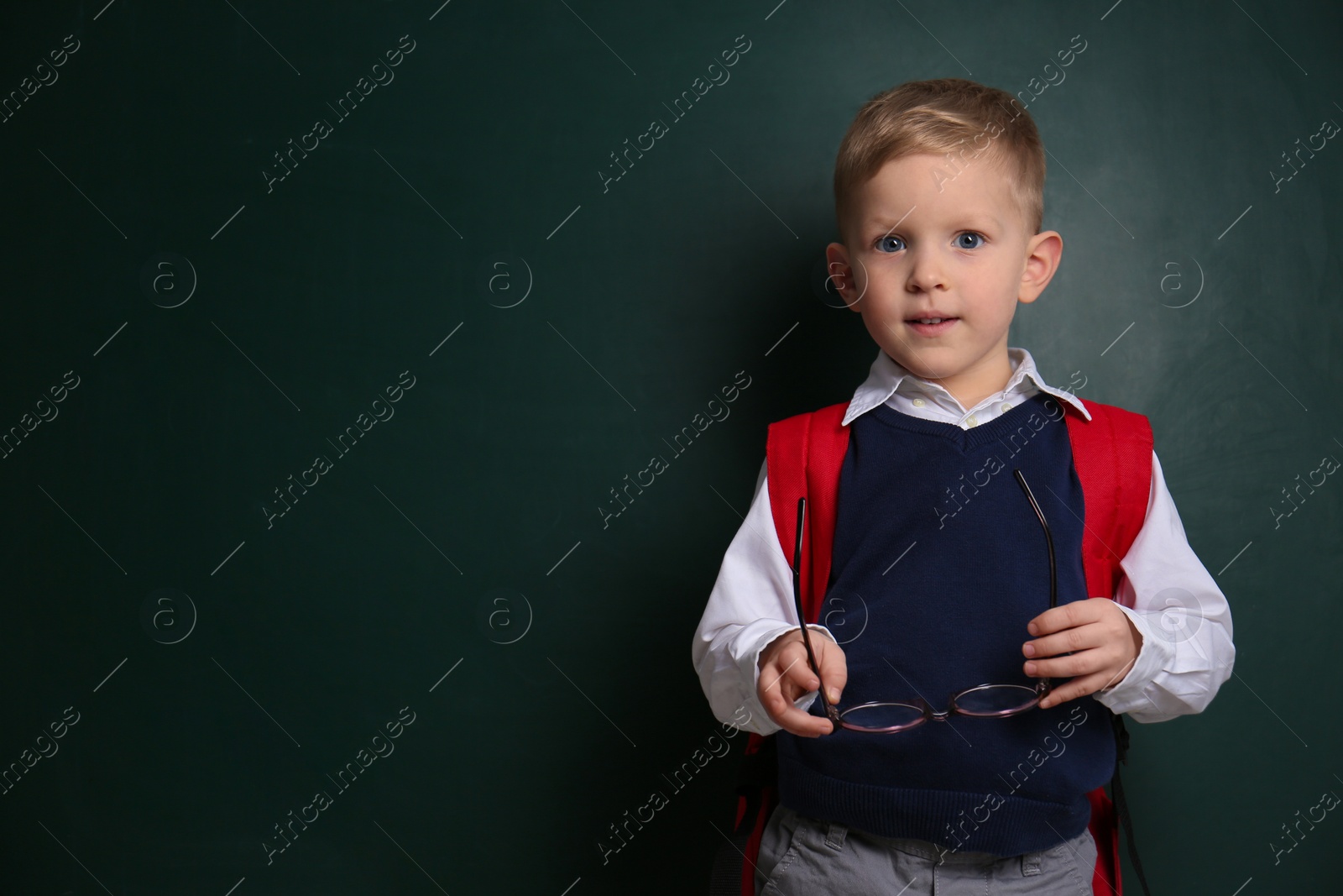 Photo of Cute little child near chalkboard, space for text. First time at school