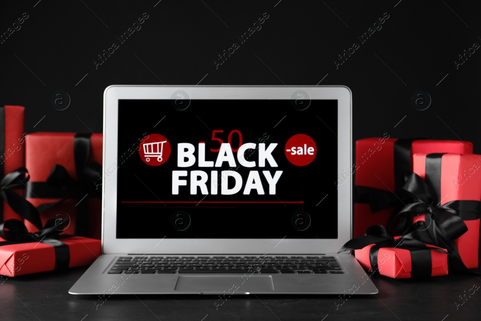 Photo of Laptop and gift boxes on table. Black Friday sale