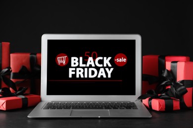 Laptop and gift boxes on table. Black Friday sale