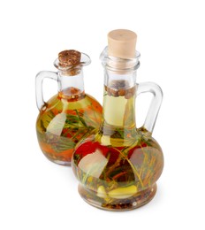 Photo of Glass jugs of cooking oils with spices and herbs on white background