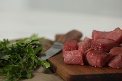 Photo of Pieces of raw beef and parsley on table, closeup