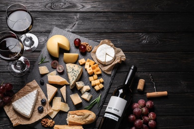 Photo of Different types of delicious cheese served on black wooden table, top view