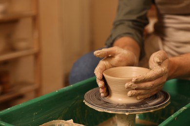 Photo of Clay crafting. Man making bowl on potter's wheel indoors, closeup. Space for text