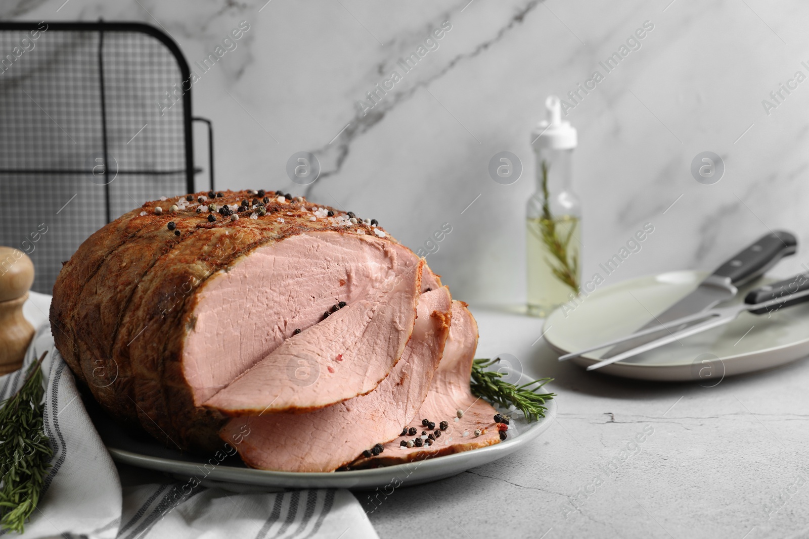 Photo of Delicious baked ham and rosemary on light grey table. Space for text