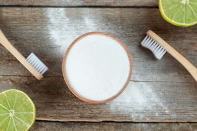 Photo of Bamboo toothbrushes, lemon and bowl of baking soda on wooden table, flat lay