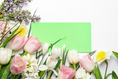 Photo of Fresh spring flowers and blank card on white background, top view. Space for text