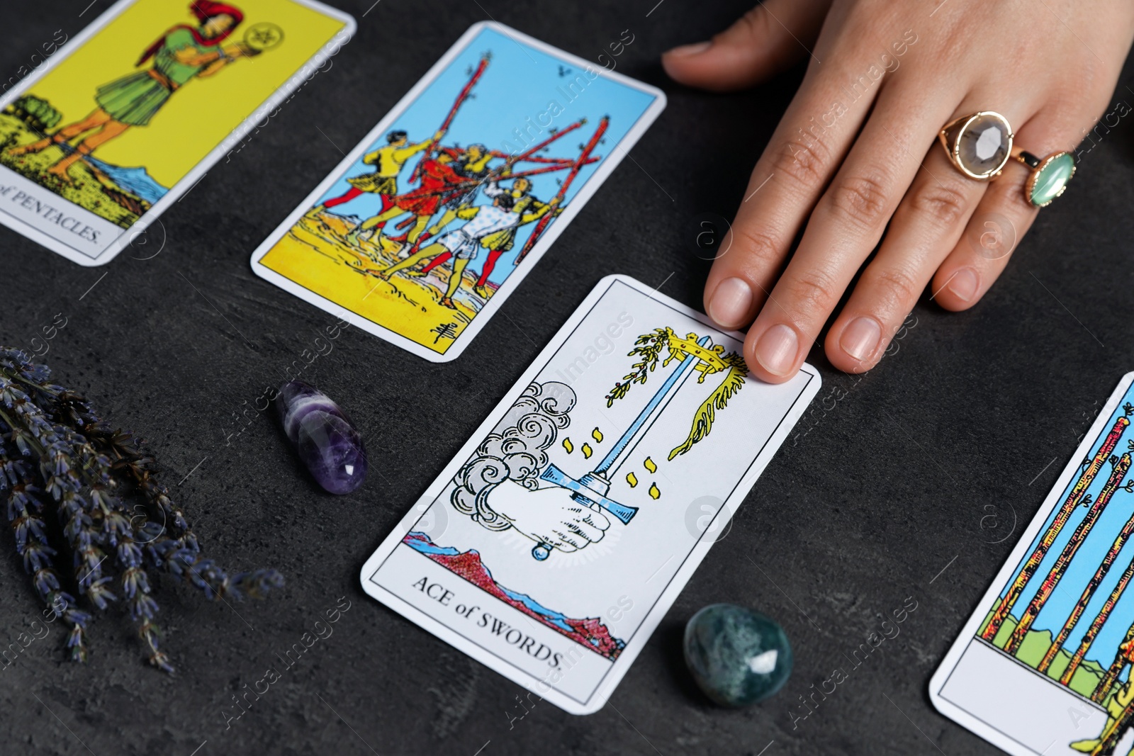 Photo of Fortune teller predicting future on spread of tarot cards at grey table, closeup