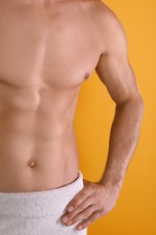 Photo of Shirtless man with slim body and towel wrapped around his hips on yellow background, closeup