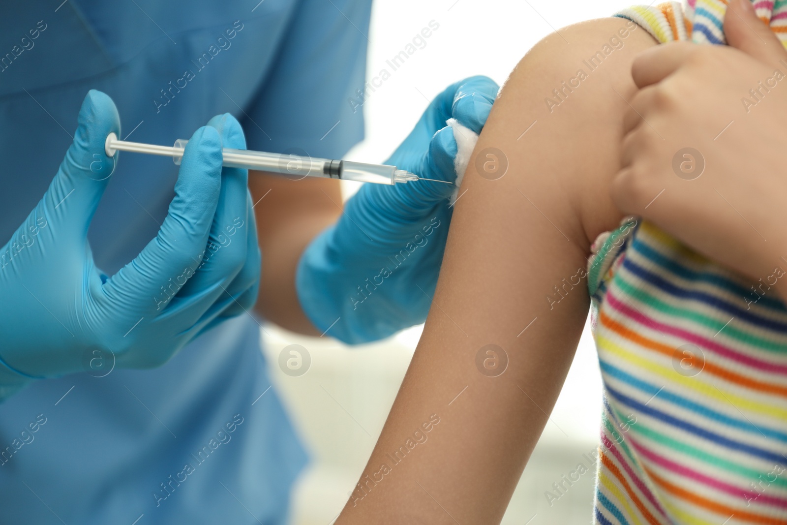 Photo of Doctor vaccinating little child in clinic, closeup