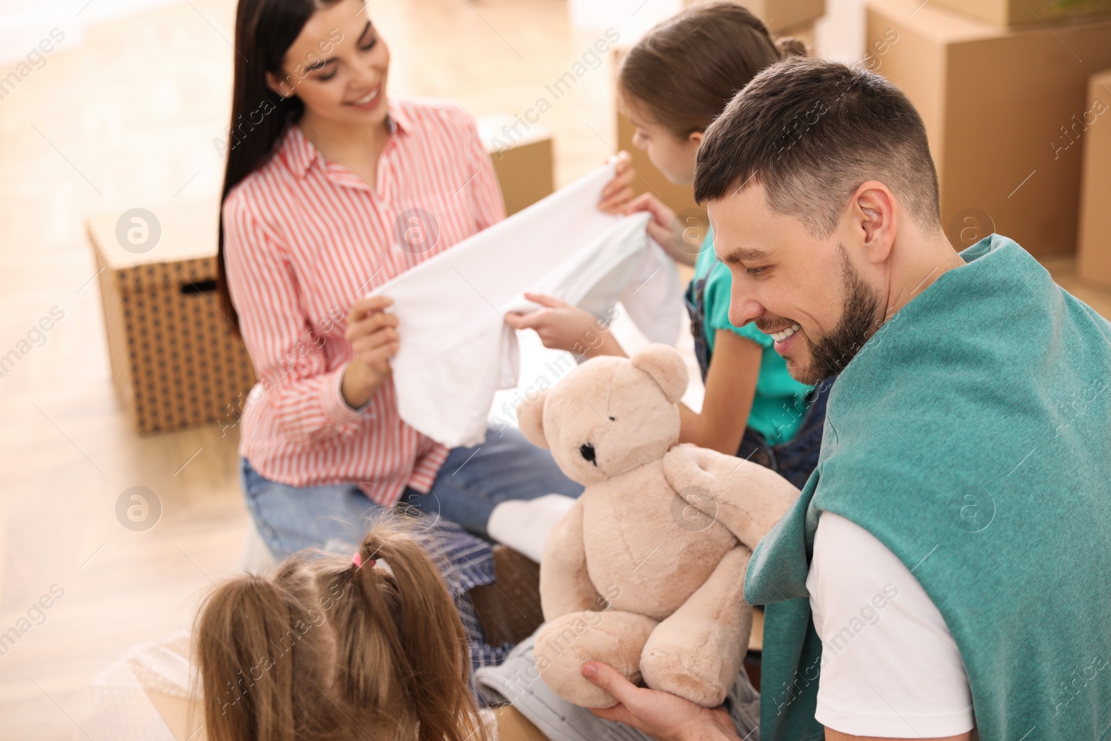 Photo of Happy family unpacking moving box in new house