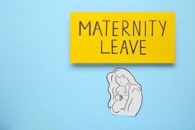 Photo of Maternity leave concept. Note and paper cutout on light blue background, flat lay with space for text
