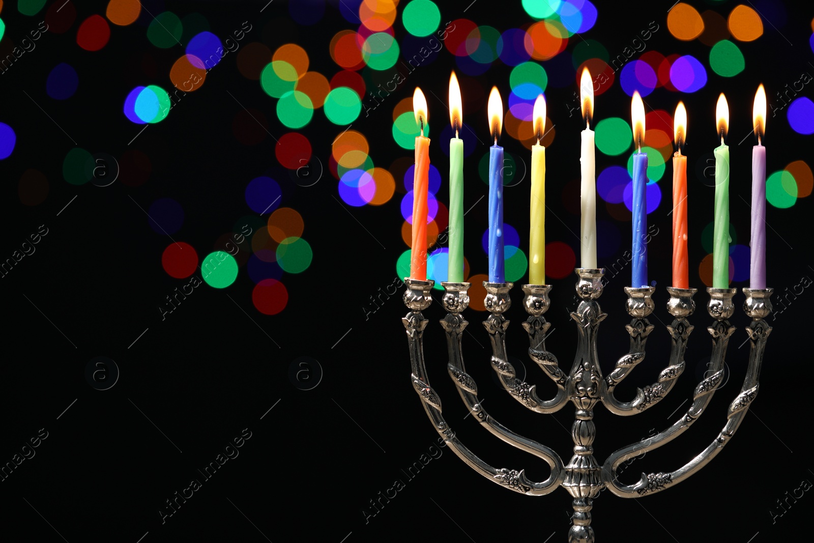 Photo of Hanukkah celebration. Menorah with burning candles against dark background with blurred lights, space for text