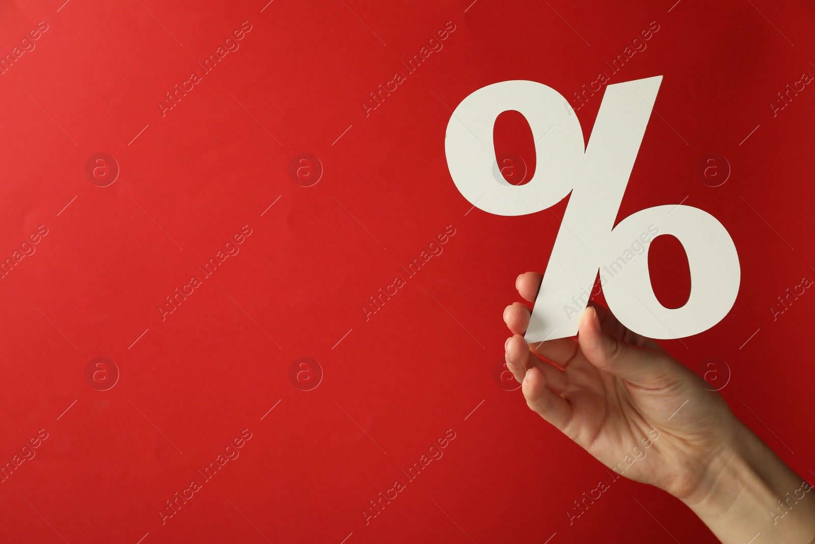 Photo of Woman holding percent sign on red background, closeup. Space for text