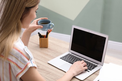 Young woman working with laptop at desk in home office