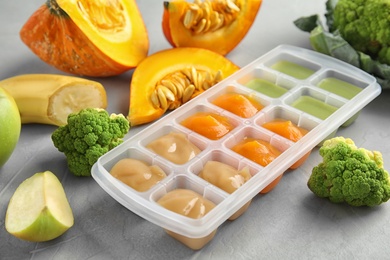 Ice cube tray with healthy baby food on table