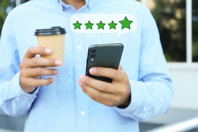 Image of Man with coffee leaving review online via smartphone outdoors, closeup. Five stars over gadget