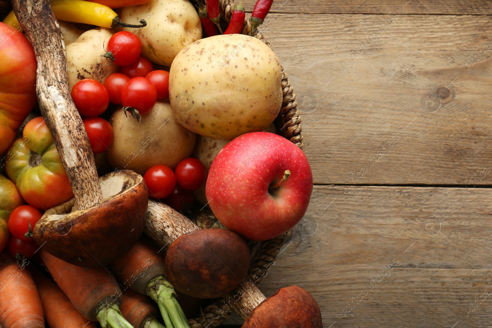 Photo of Basket with different fresh ripe vegetables and fruits on wooden table, top view. Space for text