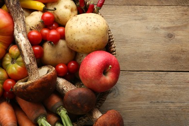 Photo of Basket with different fresh ripe vegetables and fruits on wooden table, top view. Space for text