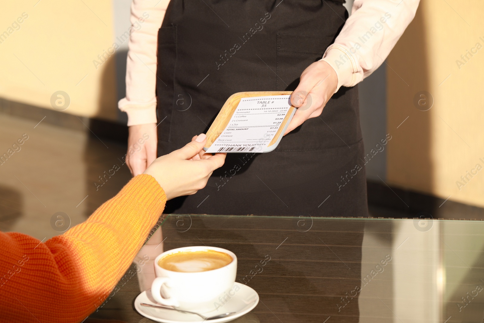 Photo of Waitress giving receipt to woman at outdoor cafe, closeup