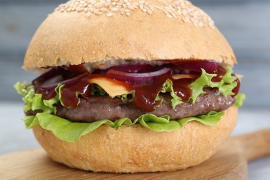 Photo of Delicious cheeseburger with lettuce, onion, ketchup and patty on blurred background, closeup