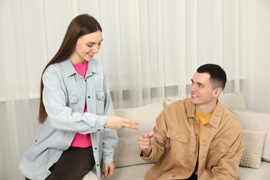 Photo of Happy people playing rock, paper and scissors in room