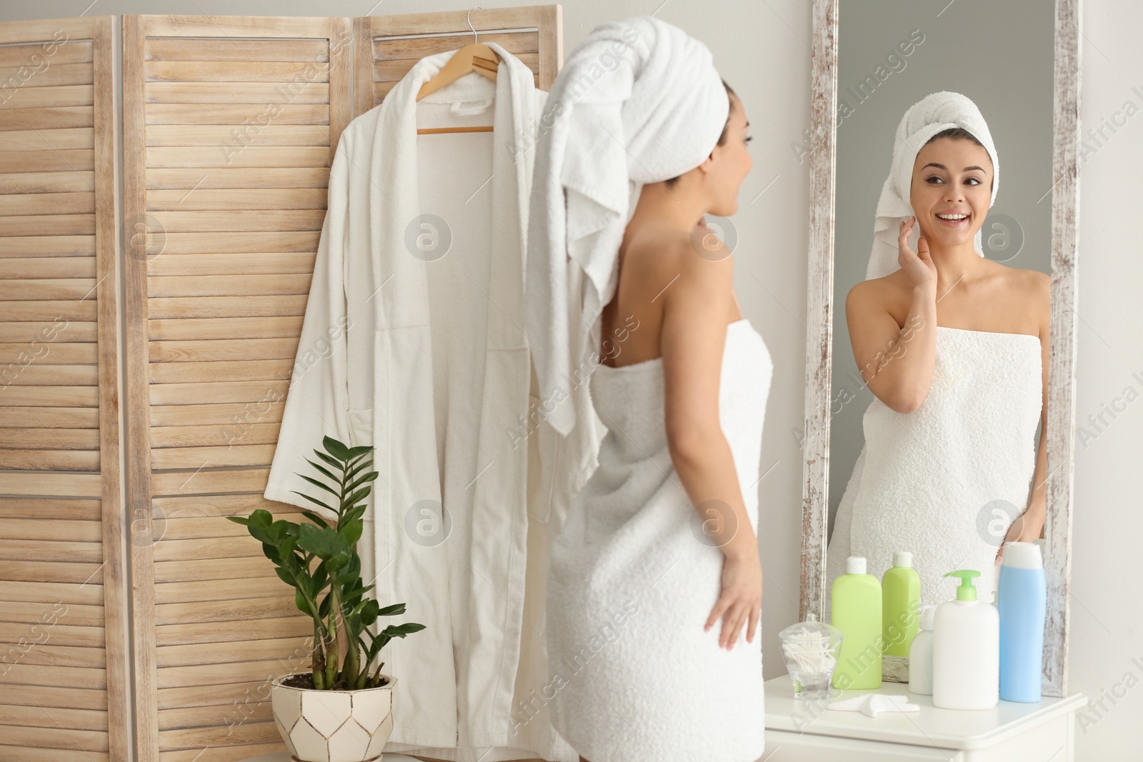 Photo of Beautiful young woman looking at herself in mirror indoors