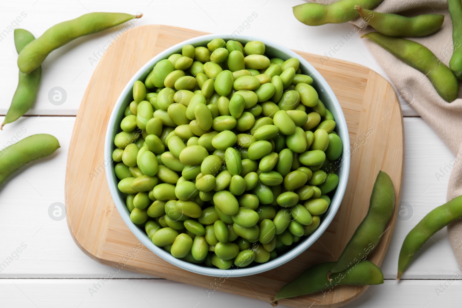 Photo of Organic edamame beans on white wooden table, flat lay