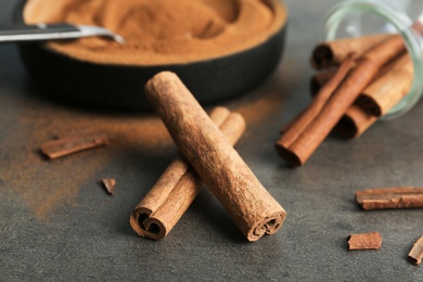 Aromatic cinnamon sticks and powder on grey background