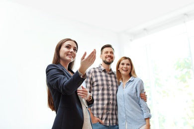 Photo of Female real estate agent showing new house to couple, indoors