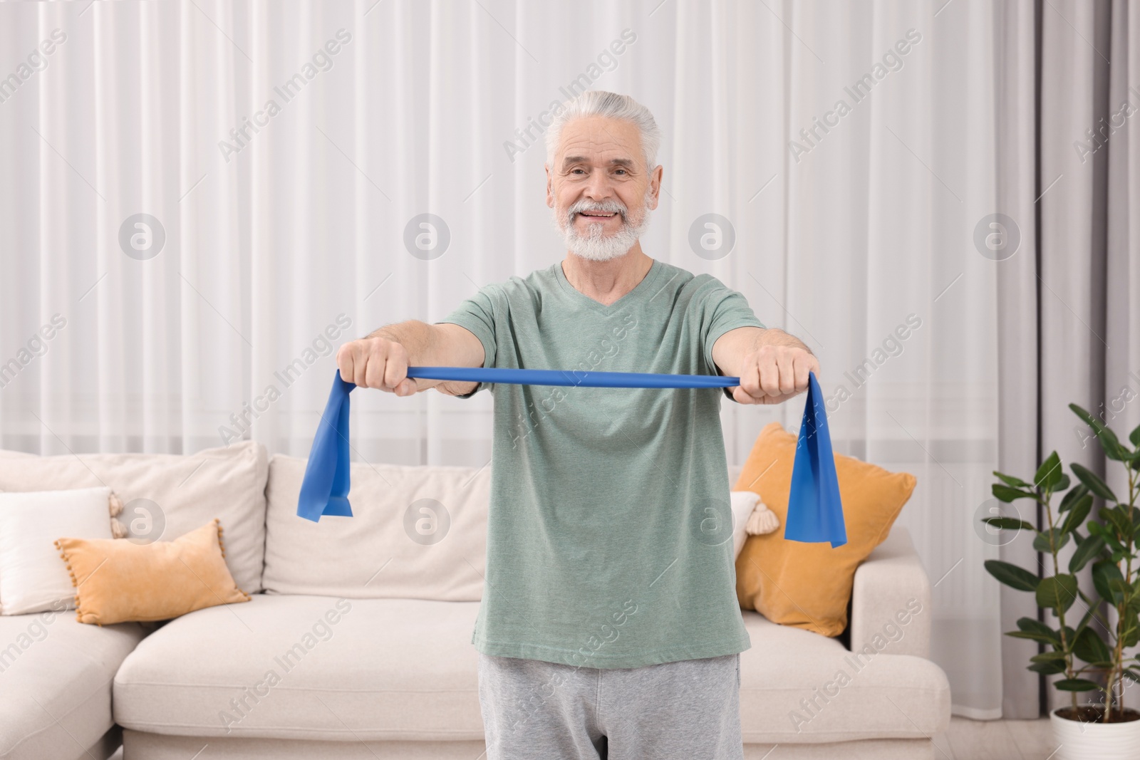 Photo of Senior man doing exercise with fitness elastic band at home