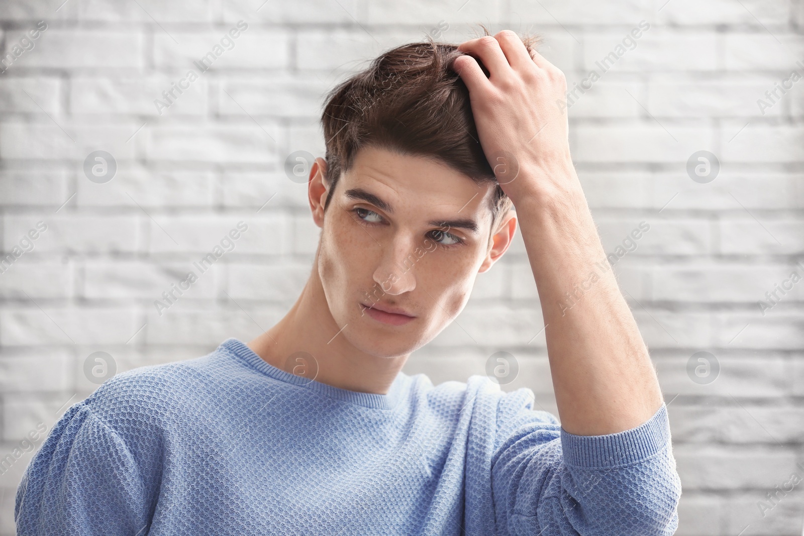 Photo of Portrait of young man with beautiful hair on brick wall background