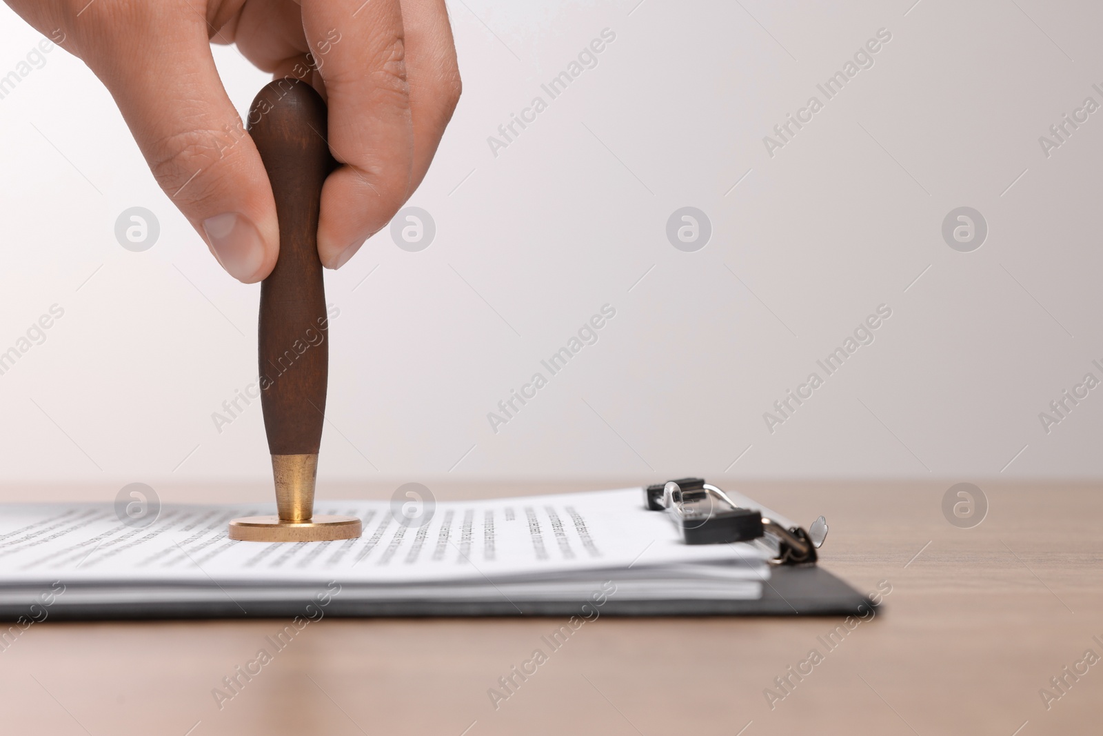 Photo of Man stamping documents at wooden table, closeup. Space for text