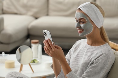 Photo of Young woman with face mask using smartphone at home, space for text. Spa treatments