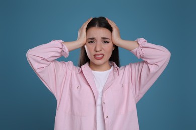Photo of Young woman suffering from headache on blue background. Cold symptoms