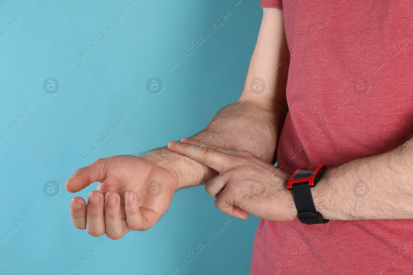 Photo of Young man checking pulse on color background, closeup. Space for text